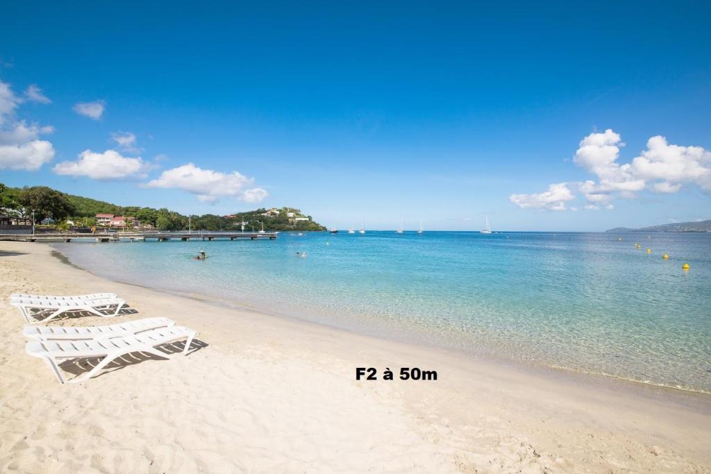 莱特鲁瓦西莱F2 proche plage Anse Mitan的两把白色椅子在靠近水面的海滩上
