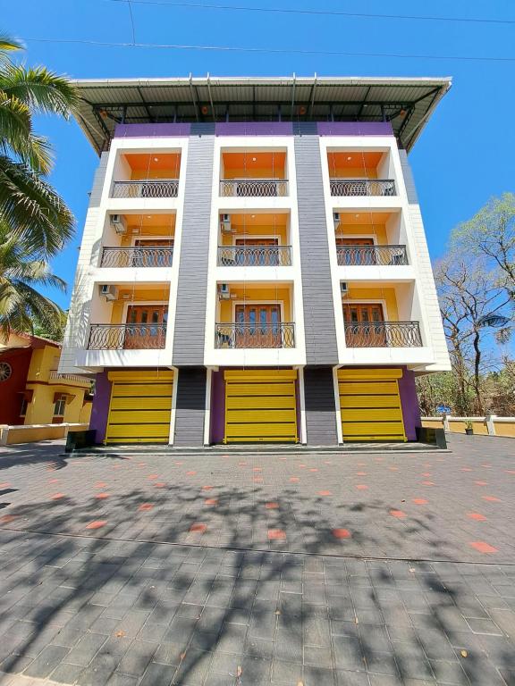TivimD'souza's Guest House的一座高大的建筑,设有黄色的门和停车场