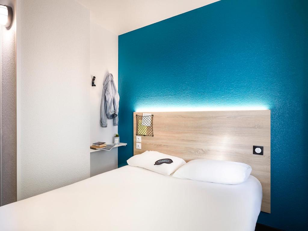 奥尔日河畔埃皮奈hotelF1 Epinay sur Orge的蓝色墙壁的房间里一张白色的床