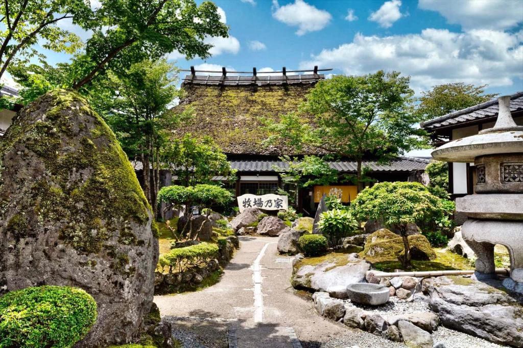 由布市Ryosou Makibanoie 18 years or older的一座拥有岩石和树木的建筑前的花园