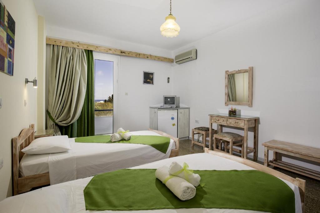 卡拉索斯卡拉托斯阳光酒店的酒店客房,配有两张带绿床单的床