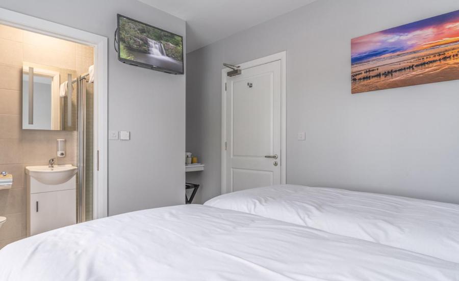 沃特福德Tramore Beach Room 5的白色卧室设有床铺和水槽