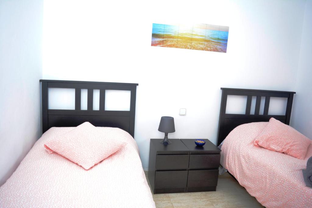 圣巴尔托洛梅Habitacion doble con baño entrada privada para huéspedes的一间卧室配有两张床和一张带台灯的桌子