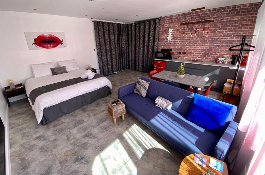 Saint DavidsDalgety Bay Luxury Studio Apartment的一间卧室配有一张床和一张蓝色的沙发
