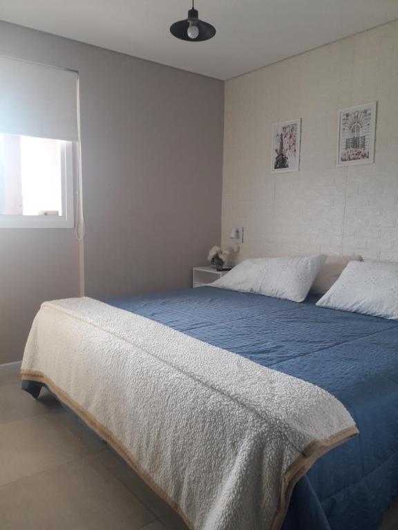 圣萨尔瓦多德朱Departamento Torre Murguía的一间卧室配有一张带蓝色床单的床和一扇窗户。