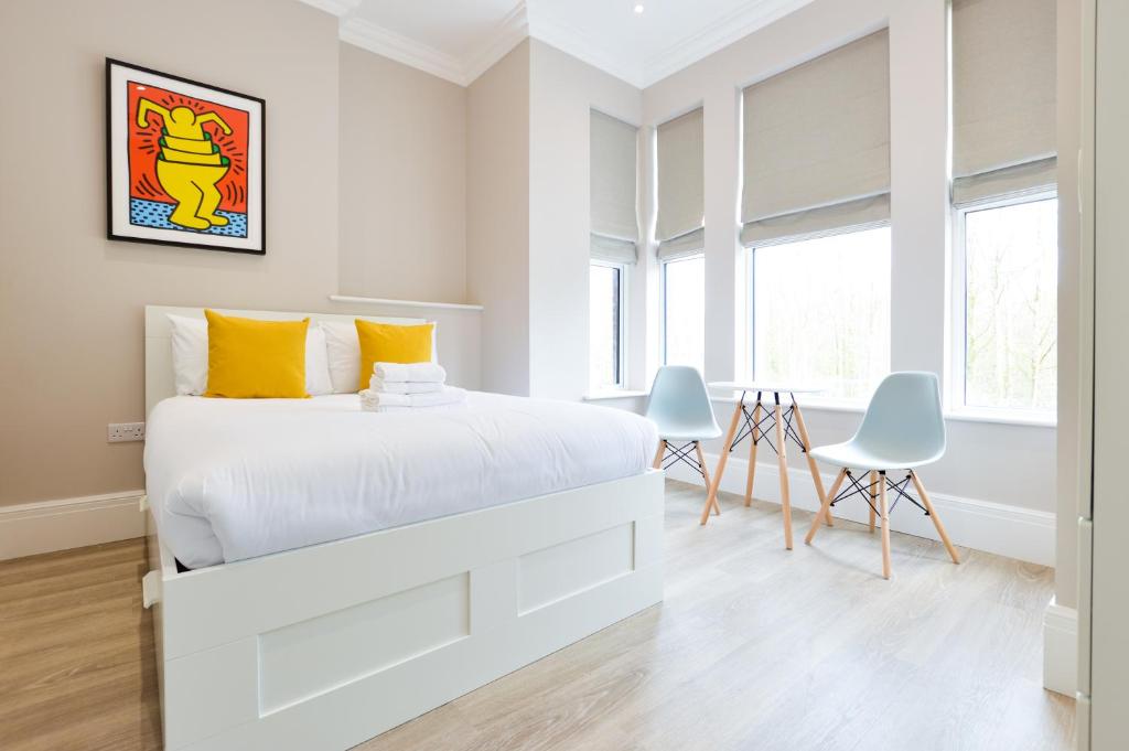 伦敦Woodview Serviced Apartments by Concept Apartments的白色卧室配有一张特大号床和两把椅子