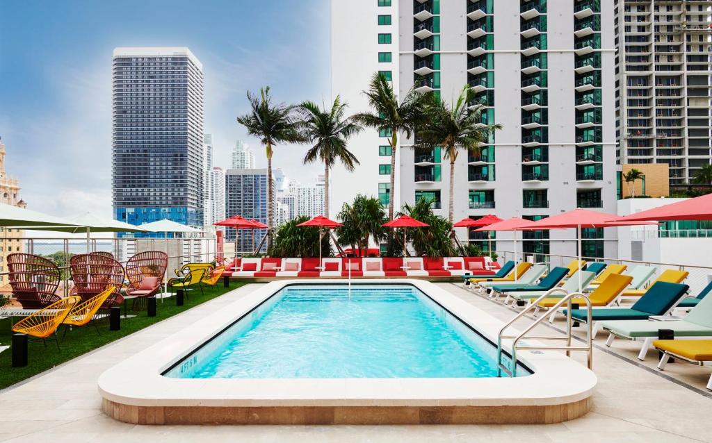 迈阿密citizenM Miami Worldcenter的一座带椅子和遮阳伞的建筑屋顶游泳池