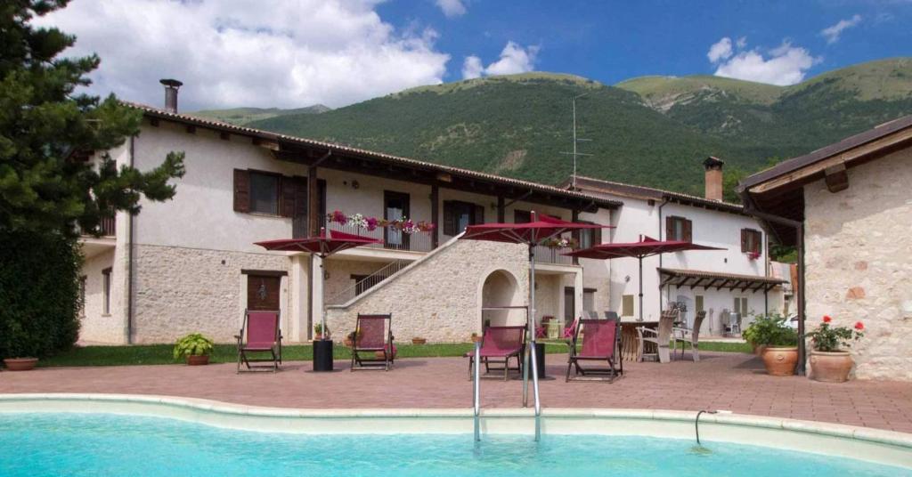 诺尔恰Agriturismo Le Case di Quarantotti的一个带游泳池和椅子的度假胜地和一座建筑