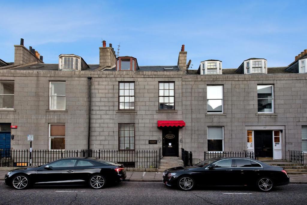 阿伯丁Inviting 9-Bed House in Aberdeen的两辆黑色汽车停在大楼前
