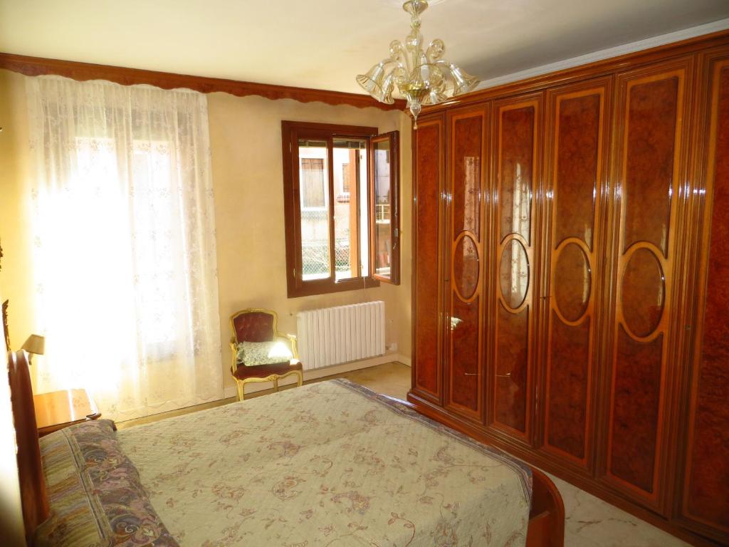 威尼斯阿斯特里亚威尼斯套房公寓的一间卧室配有一张床和一个大型木制橱柜