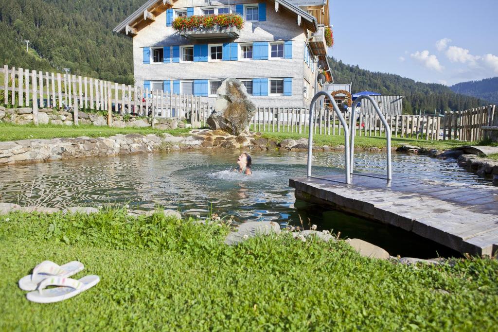 巴尔德赫旺施瓦本霍夫酒店的在房子前面的池塘里游泳的人
