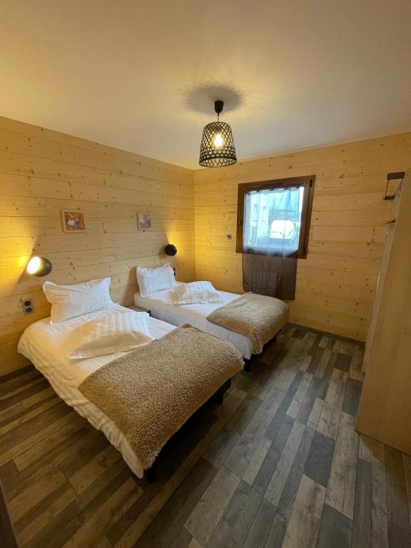 AnouldLe Chalet Du Castor的木墙客房的两张床