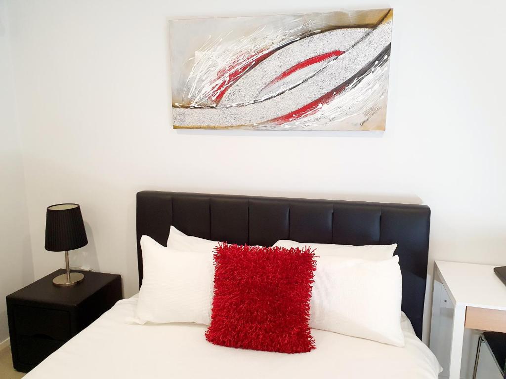珀斯M5 West Perth Studio Apartment near Kings Park的一间卧室配有一张红色枕头的床