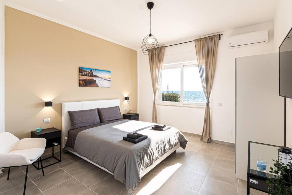 圣塔马里亚迪卡斯特Esclusivo alloggio a sfioro sul mare con terrazza.的卧室配有床、椅子和窗户。