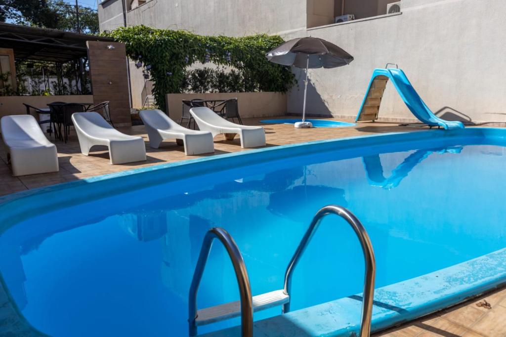 伊瓜苏劳伦斯酒店的一个带滑梯、椅子和遮阳伞的游泳池