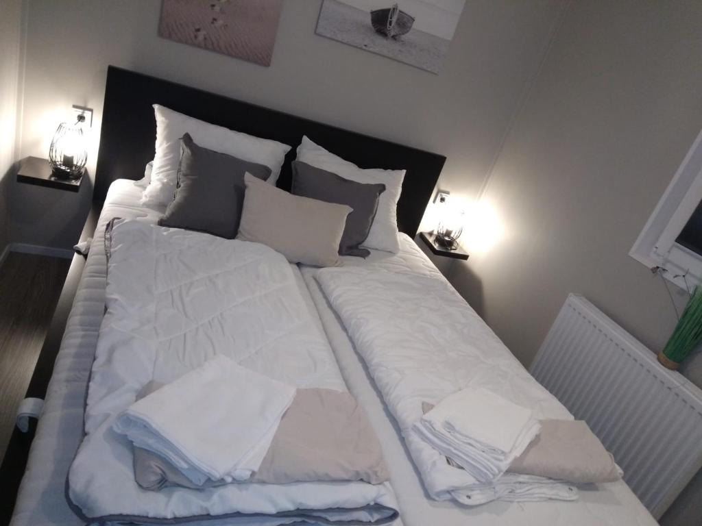 LathumFerienhaus / Chalet / Bungalow am See, Holland, Niederlande, Lathum的一张配有白色床单和枕头的大床
