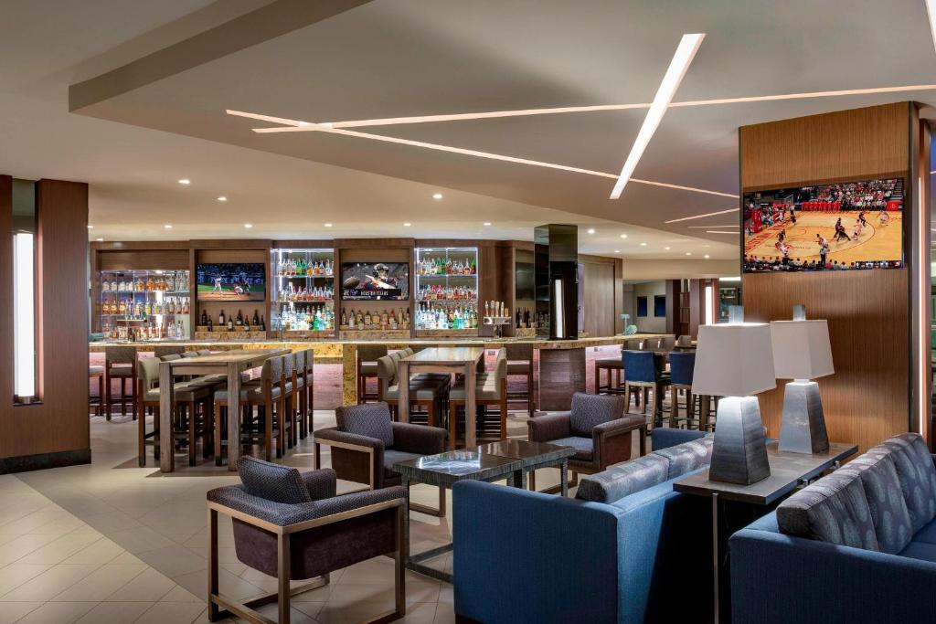 休斯顿休斯顿乔治布什洲际机场万豪酒店的餐厅设有酒吧,配有蓝色的桌椅