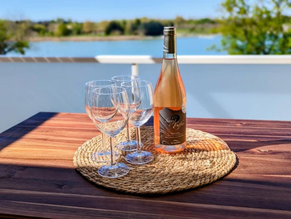 蒙特Lakeside Provence - Appartement 4 étoiles face au lac de Monteux的桌子上放有一瓶葡萄酒和两杯酒