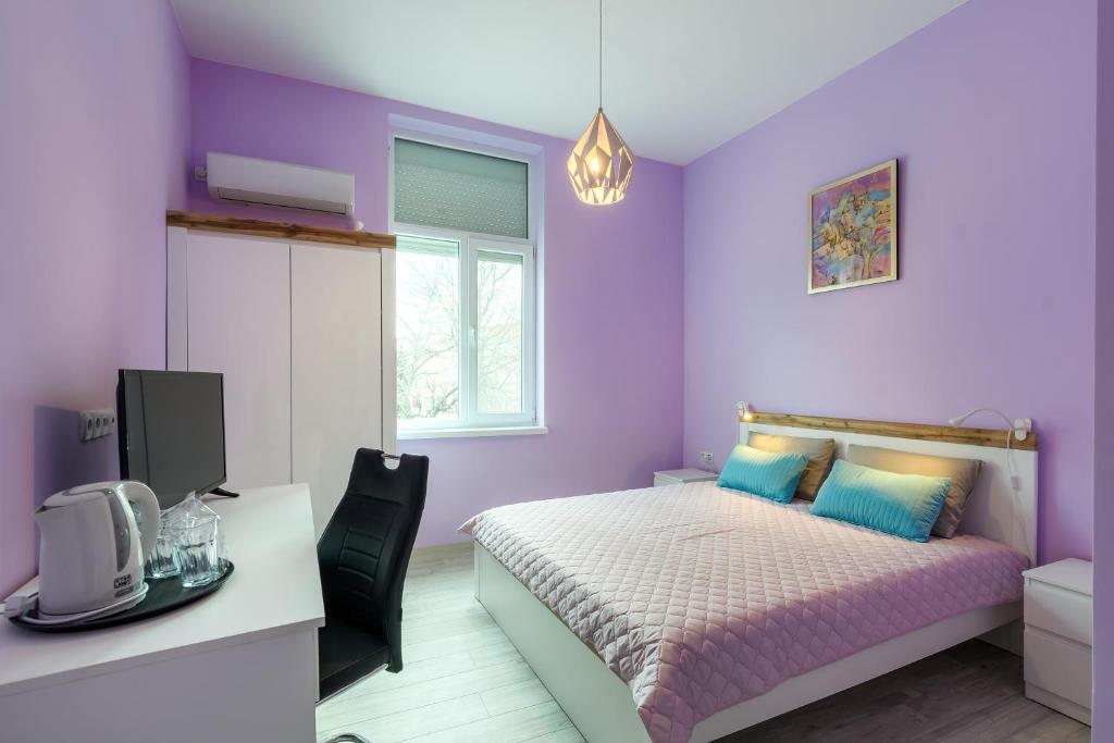 布尔加斯ПАЦО的紫色卧室配有一张床和一张书桌