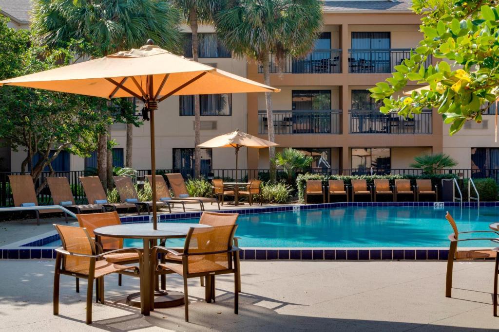 奥卡拉欧卡拉万怡酒店的游泳池旁配有桌椅和遮阳伞