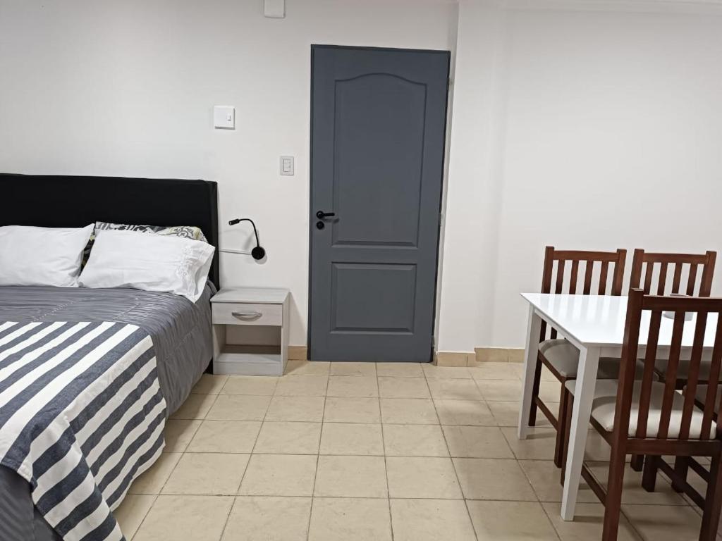 里奥加耶戈斯Hermoso departamento en Rio Gallegos的卧室配有1张床、1张桌子和1张桌子以及椅子。