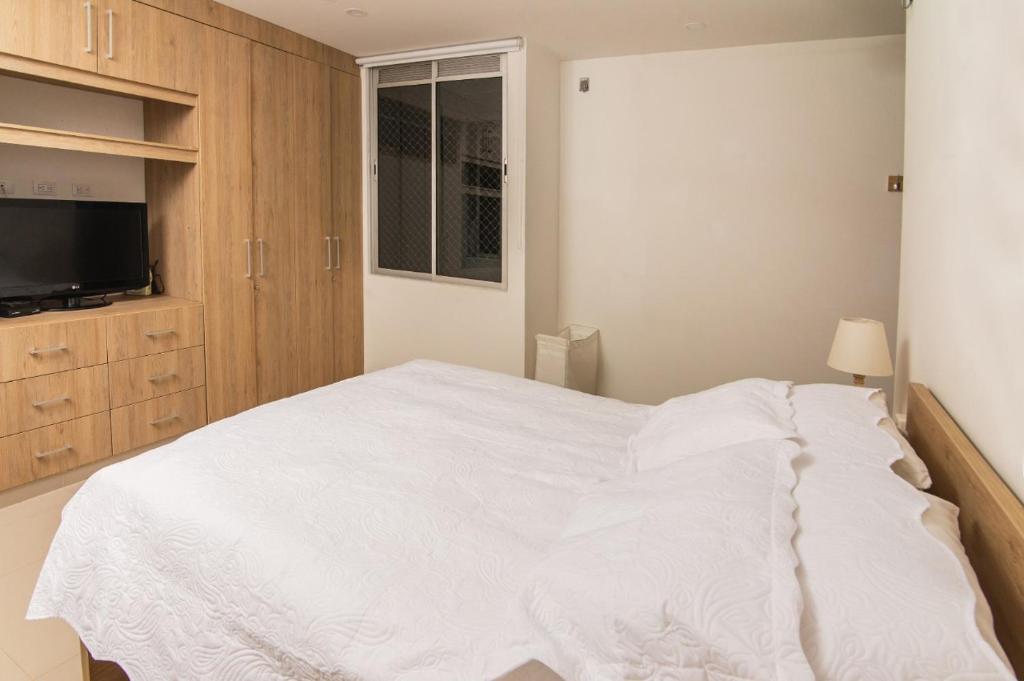 蒙特里亚Apartamento acogedor的卧室配有白色的床和电视。