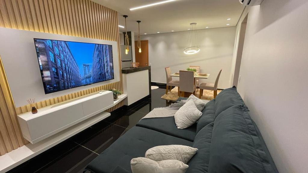 戈亚尼亚Condomínio encantador de luxo的客厅配有沙发和墙上的电视