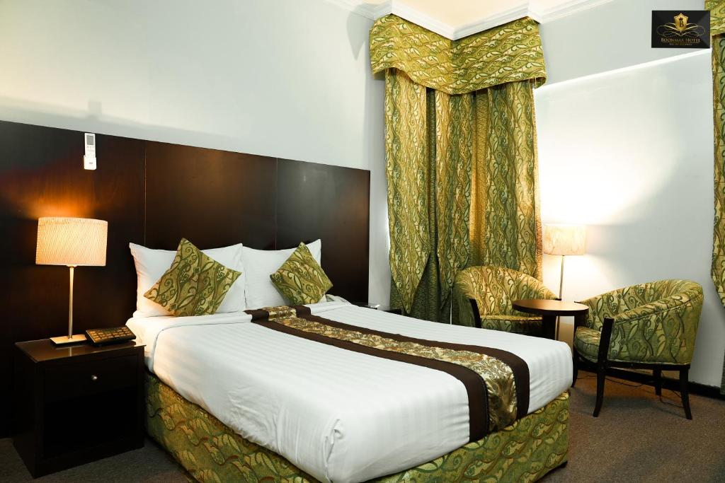 迪拜BOONMAX Hotel的酒店客房带一张大床和一把椅子