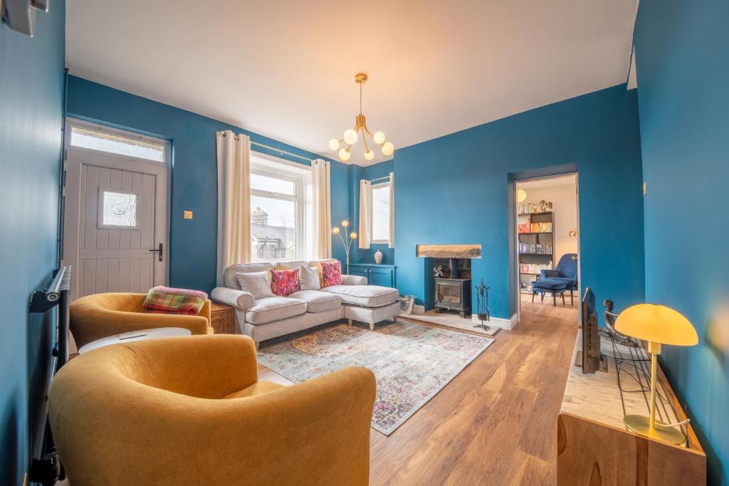 马特洛克Corner Cottage的客厅拥有蓝色的墙壁,配有沙发和椅子