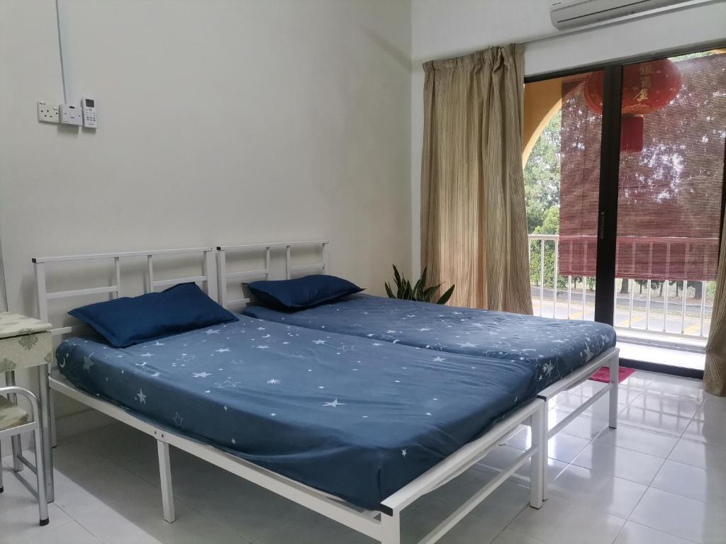 马六甲EBH INN的窗户客房内的一张带蓝色床单的床