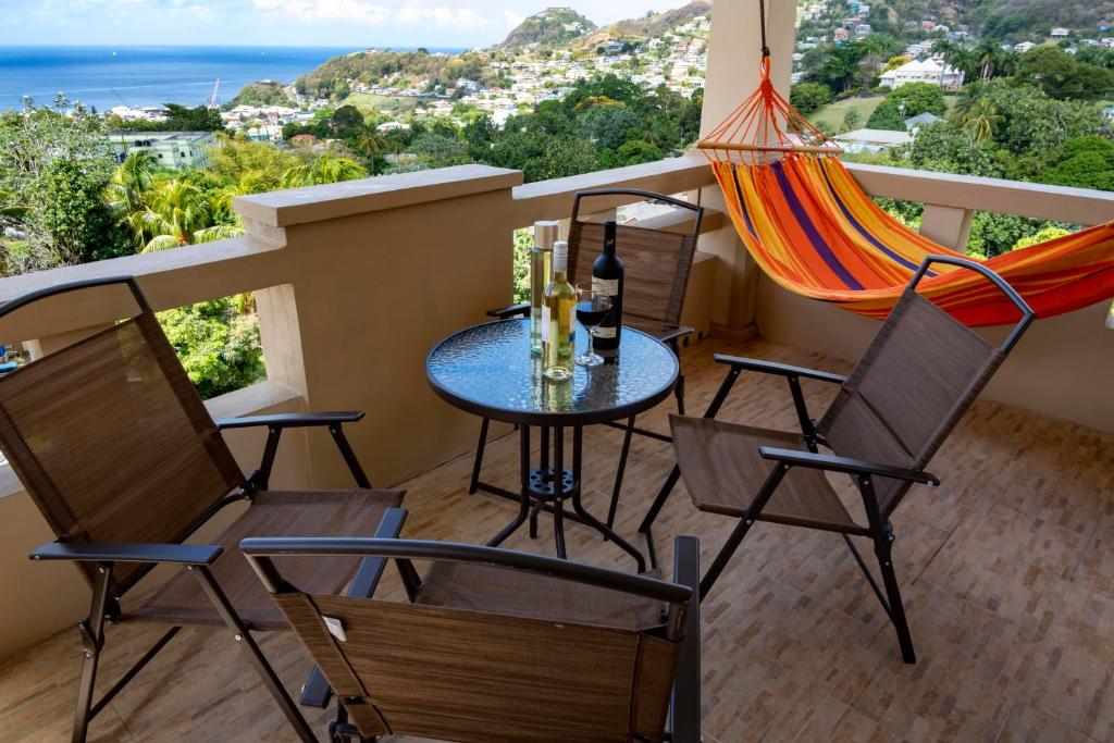 金斯敦Royal Bliss Apartment Suites的阳台配有桌椅和吊床。