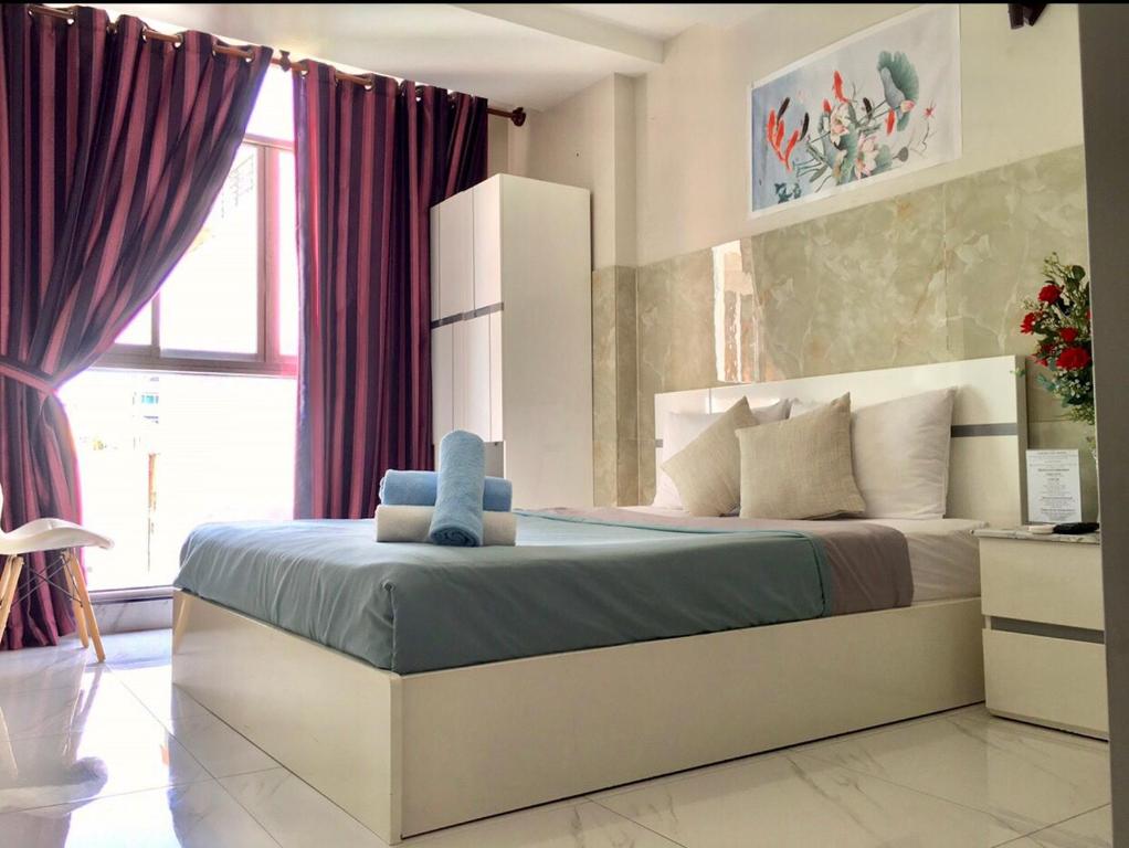 胡志明市Saigon Cozy Hotel的一间卧室配有一张大床和紫色窗帘