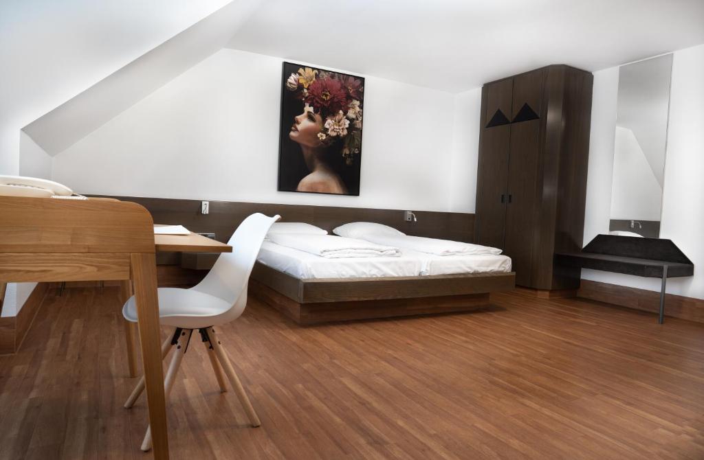 海尔布隆海尔布隆城市酒店的一间卧室配有一张床、一张桌子和一幅画