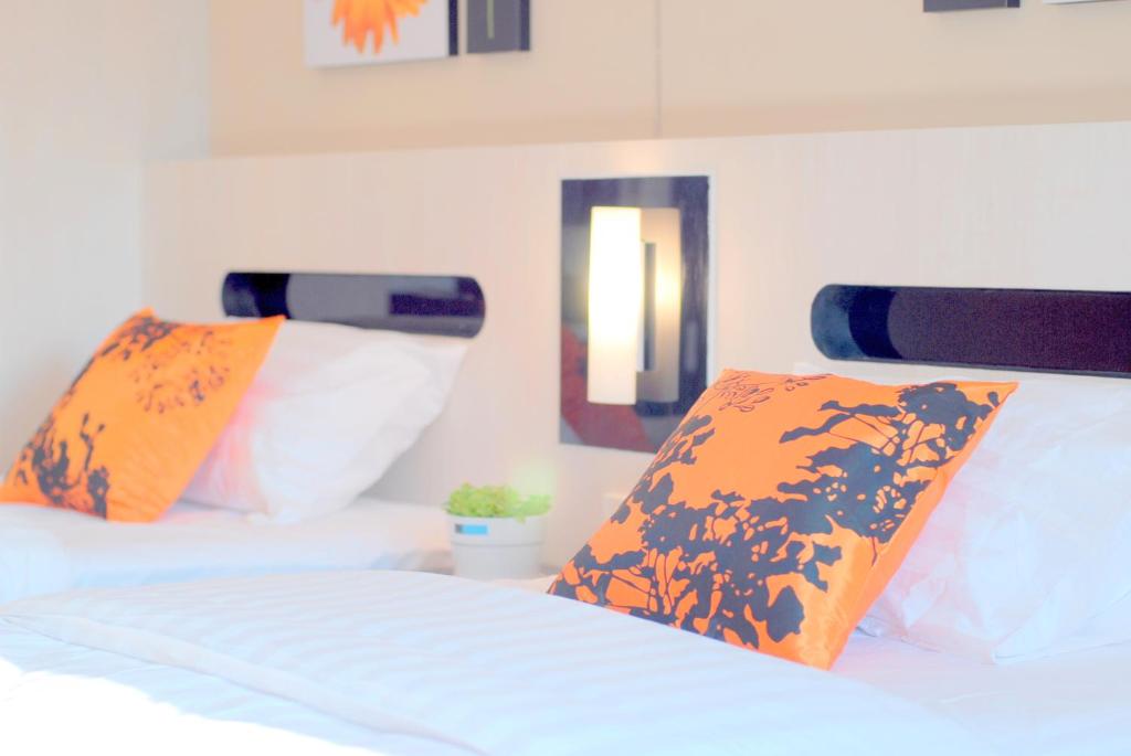 曼谷萨拉达恩假日酒店的一间卧室配有两张带橙色和白色枕头的床