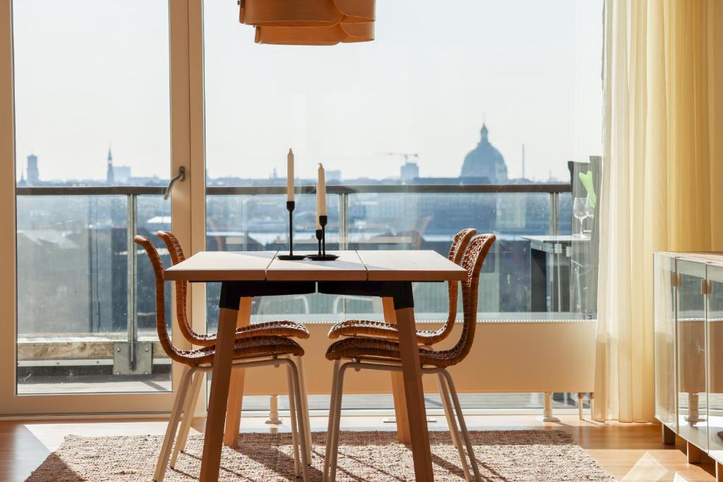 哥本哈根Penthouse - Amazing views & hygge的餐桌、椅子和大窗户
