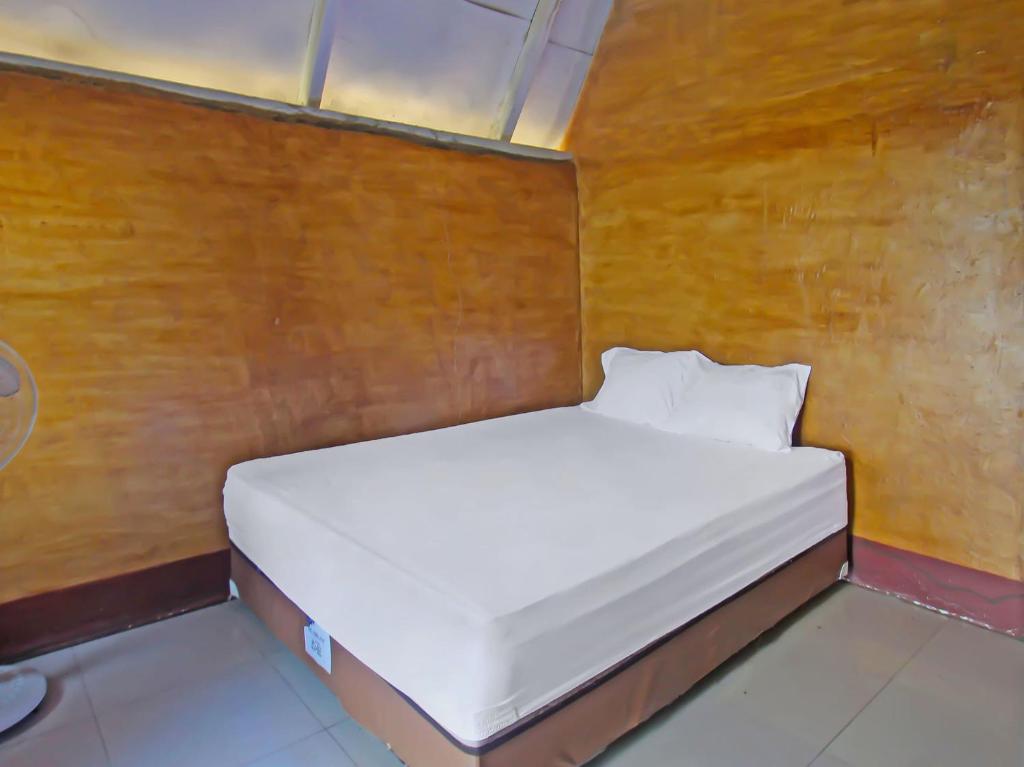 LukOYO 92419 Rejeng Homestay Near Kerta Gangga Waterfall的木墙客房内的一张白色床