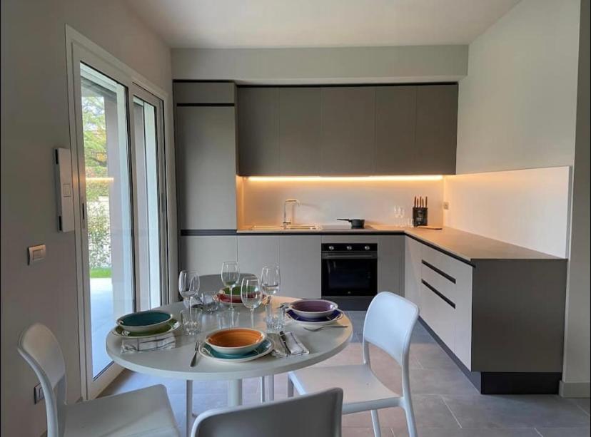 阿斯蒂Grazioso appartamento con giardino privato的厨房配有白色的桌椅和玻璃杯桌子