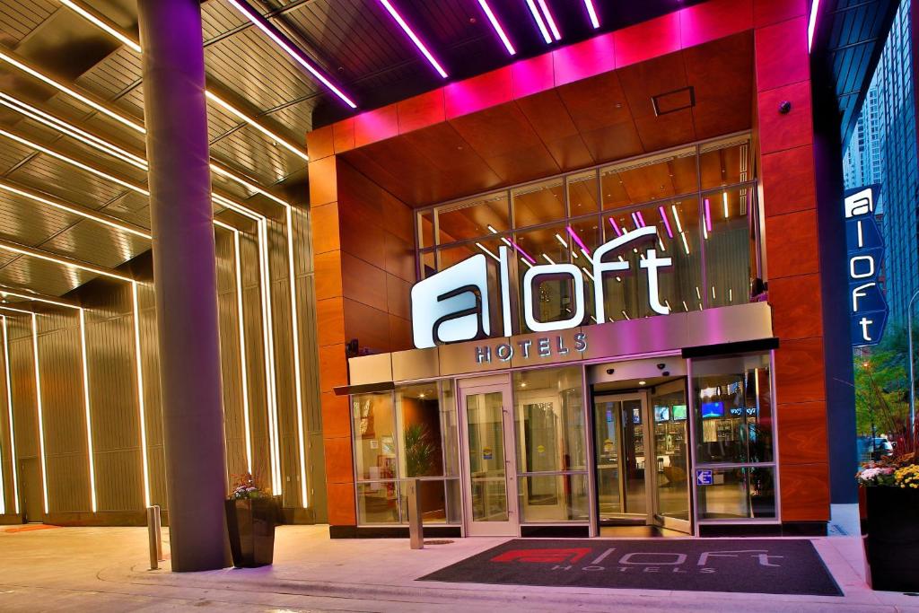 芝加哥Aloft Chicago Mag Mile的 ⁇ 虹灯标志的酒店前方的商店