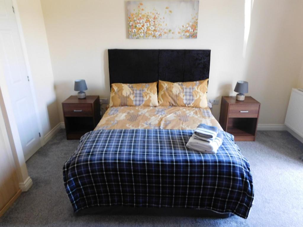 福尔柯克Double room with ensuite, tea & coffee, Falkirk, Scotland的一间卧室配有一张带2个床头柜和2张桌子的床