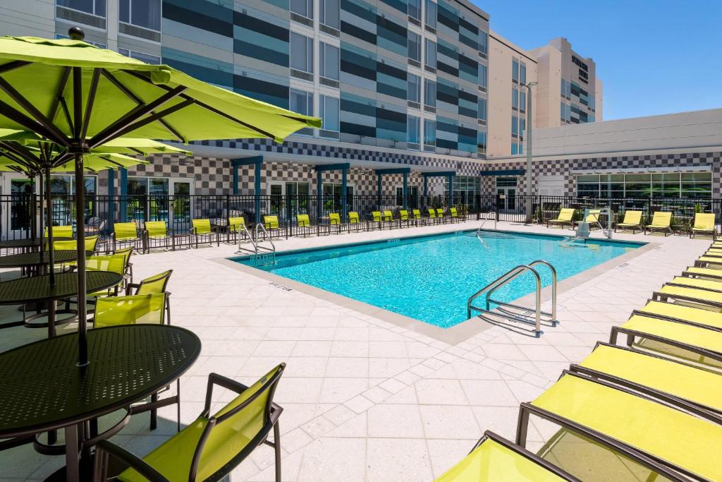 莱克兰SpringHill Suites Lakeland的一座带桌椅的游泳池以及一座建筑