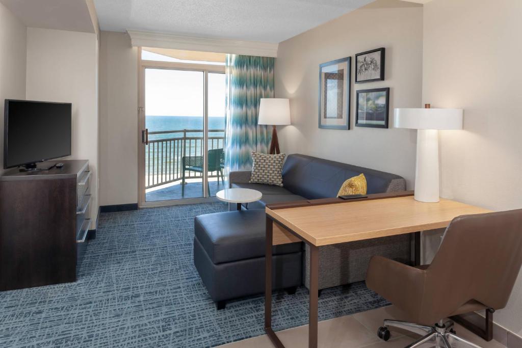 弗吉尼亚海滩万豪弗吉尼亚海滩海滨酒店的酒店客房配有书桌、沙发和电视。