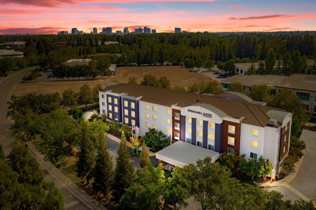 萨克拉门托SpringHill Suites by Marriott Sacramento Natomas的建筑的顶部景色,背景是日落