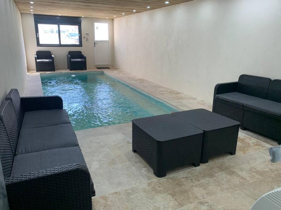 拉弗雷切Villa piscine/spa privé intérieur 33° ZOO DE LA FLECHE 24h DU MANS的一个带椅子、沙发和桌子的游泳池