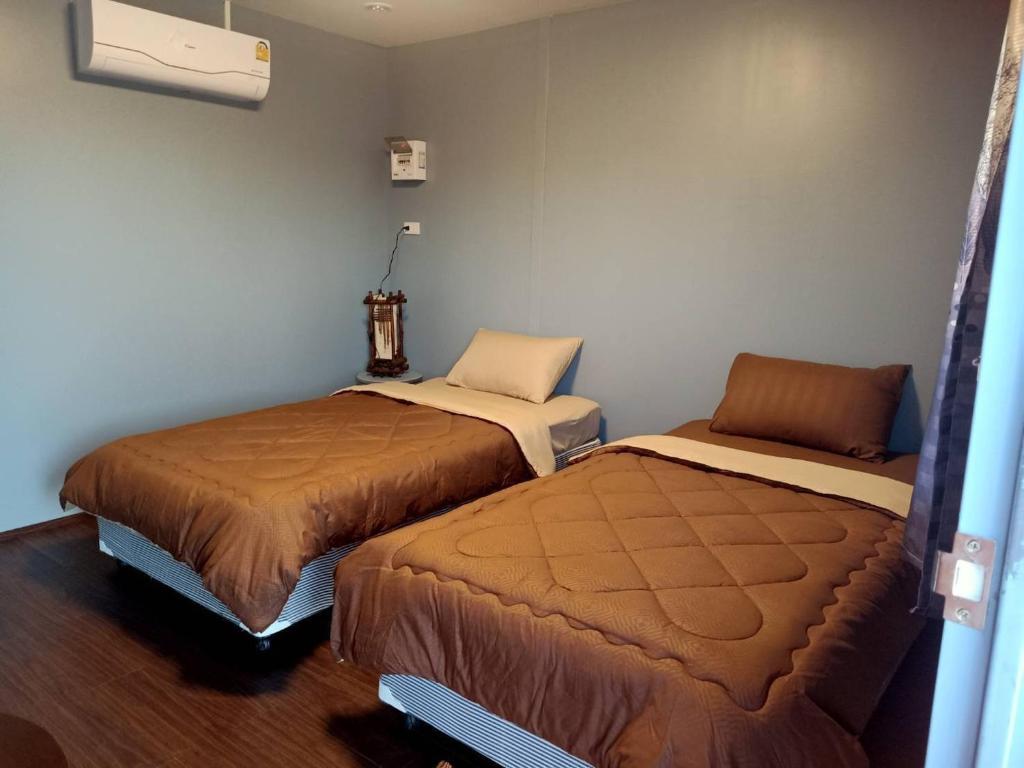 Ban Don Klangเฮือนพรนาคา โฮมสเตย์的一间客房内配有两张床的房间