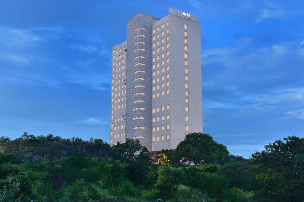 海得拉巴Fairfield by Marriott Hyderabad Gachibowli的一座高大的建筑,位于山顶上,树木繁茂