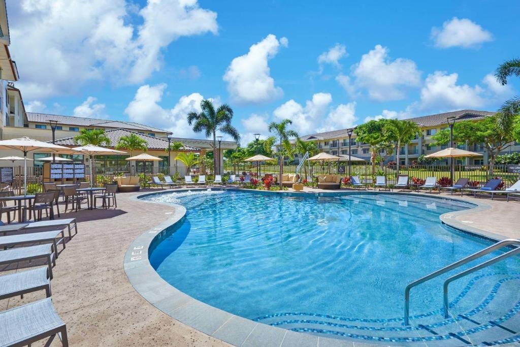 卡波雷Residence Inn by Marriott Oahu Kapolei的度假村的游泳池,配有椅子和遮阳伞