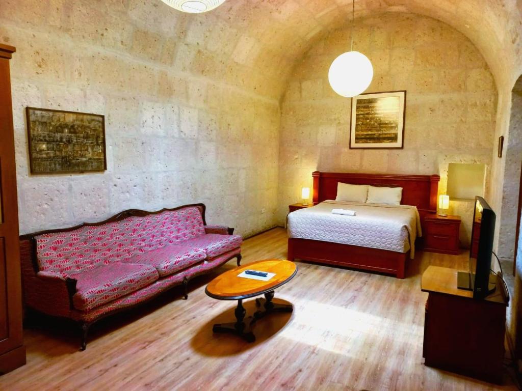 阿雷基帕Casablanca Hostal的一间卧室配有一张床、一张沙发和一张桌子