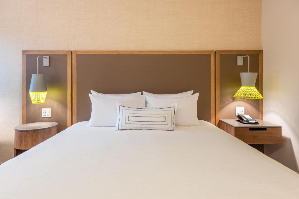 麦德林Fairfield by Marriott Medellin Sabaneta的一间卧室配有一张带两盏灯的大型白色床。