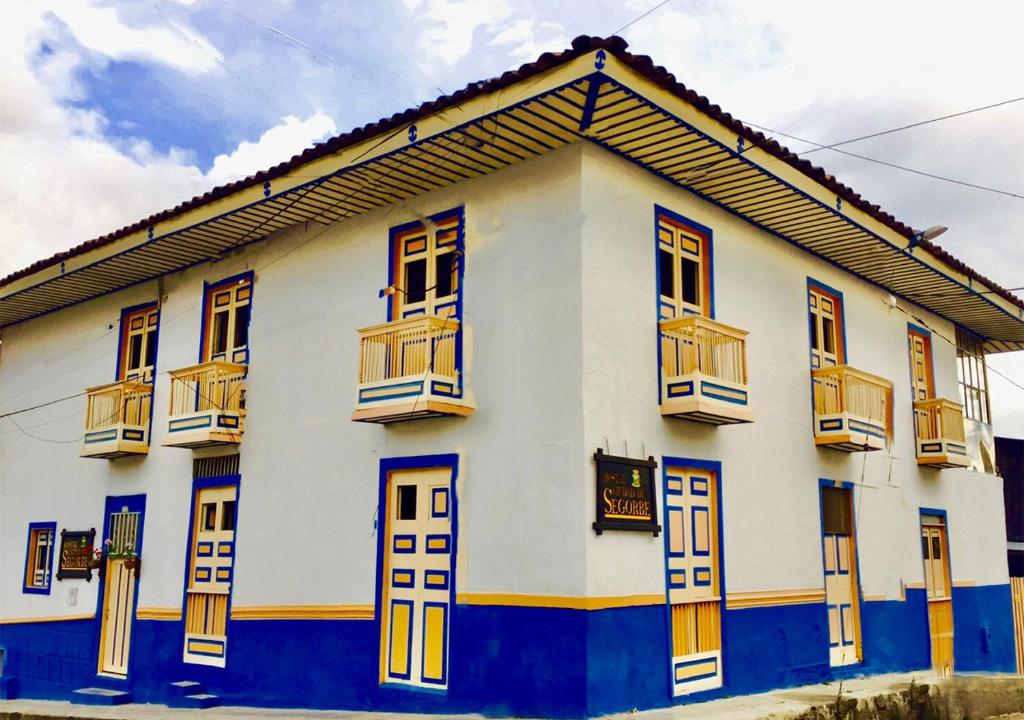 萨兰托Hostal Ciudad de Segorbe的白色和蓝色的建筑,设有窗户和阳台