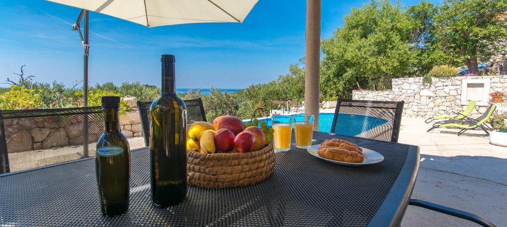 巴比诺波尔杰Mljet, old stone apartment with pool in nature的一张桌子,上面放着一篮水果和两瓶葡萄酒